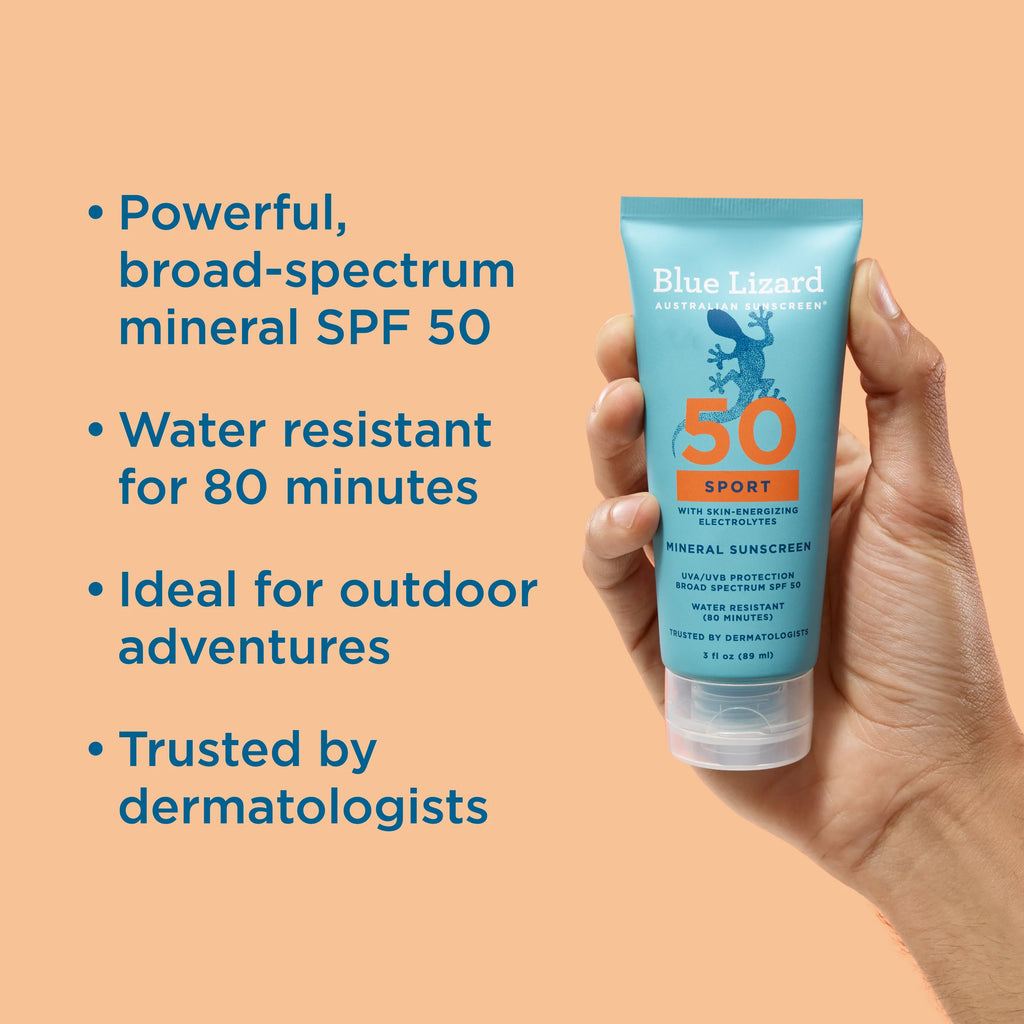 Hand holding a Blue Lizard Sport SPF 50 mineral sunscreen tube with product features listed on an orange background